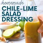 A hand holds a bottle of salad dressing in front of a plate of ingredients. A text overlay reads "Homemade Chile Lime Salad Dressing"