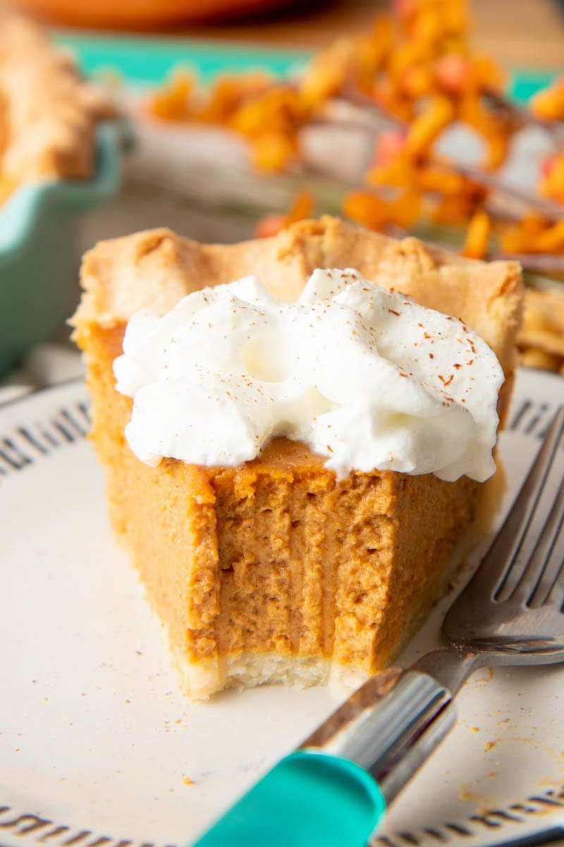 Front view of a slice of pumpkin pie with a bite out of it.