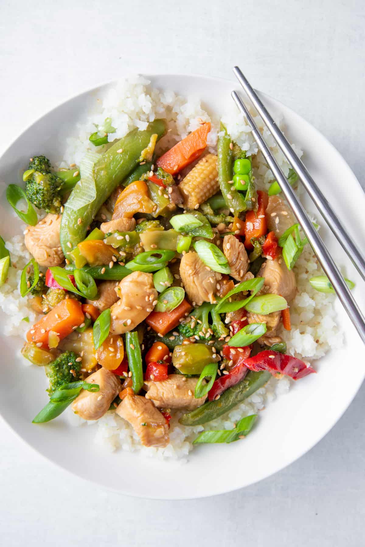 An overhead shot of stir fry in a bowl with chopsticks.