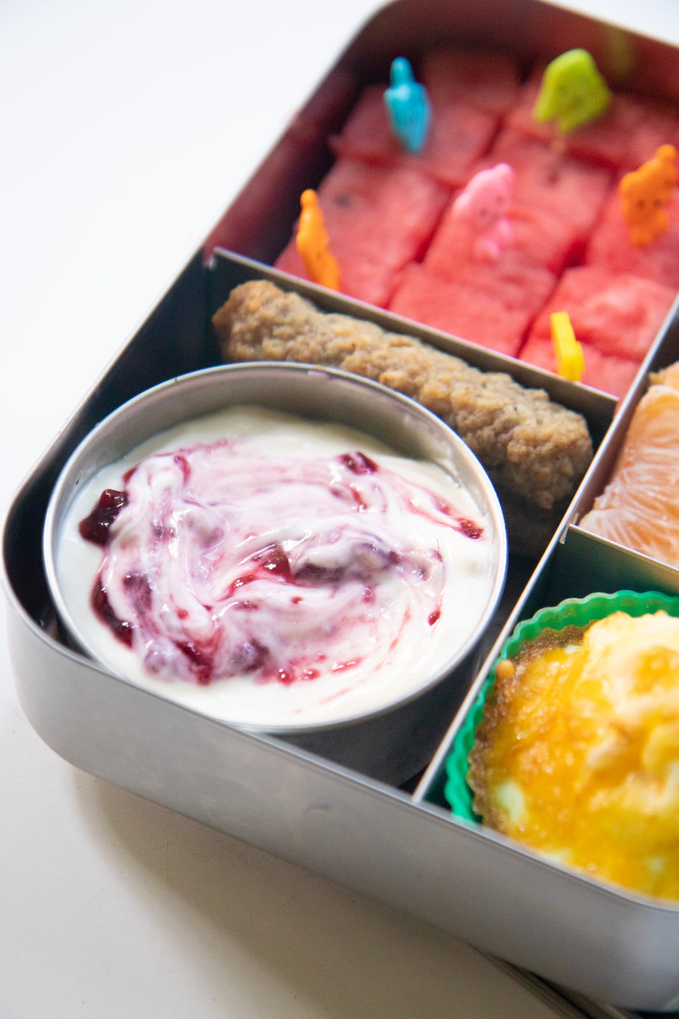 Metal bento-style lunchbox filled with breakfast items.