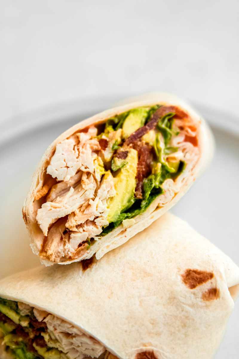 Cross section of a cut chicken bacon ranch wrap showing all the ingredients wrapped inside.