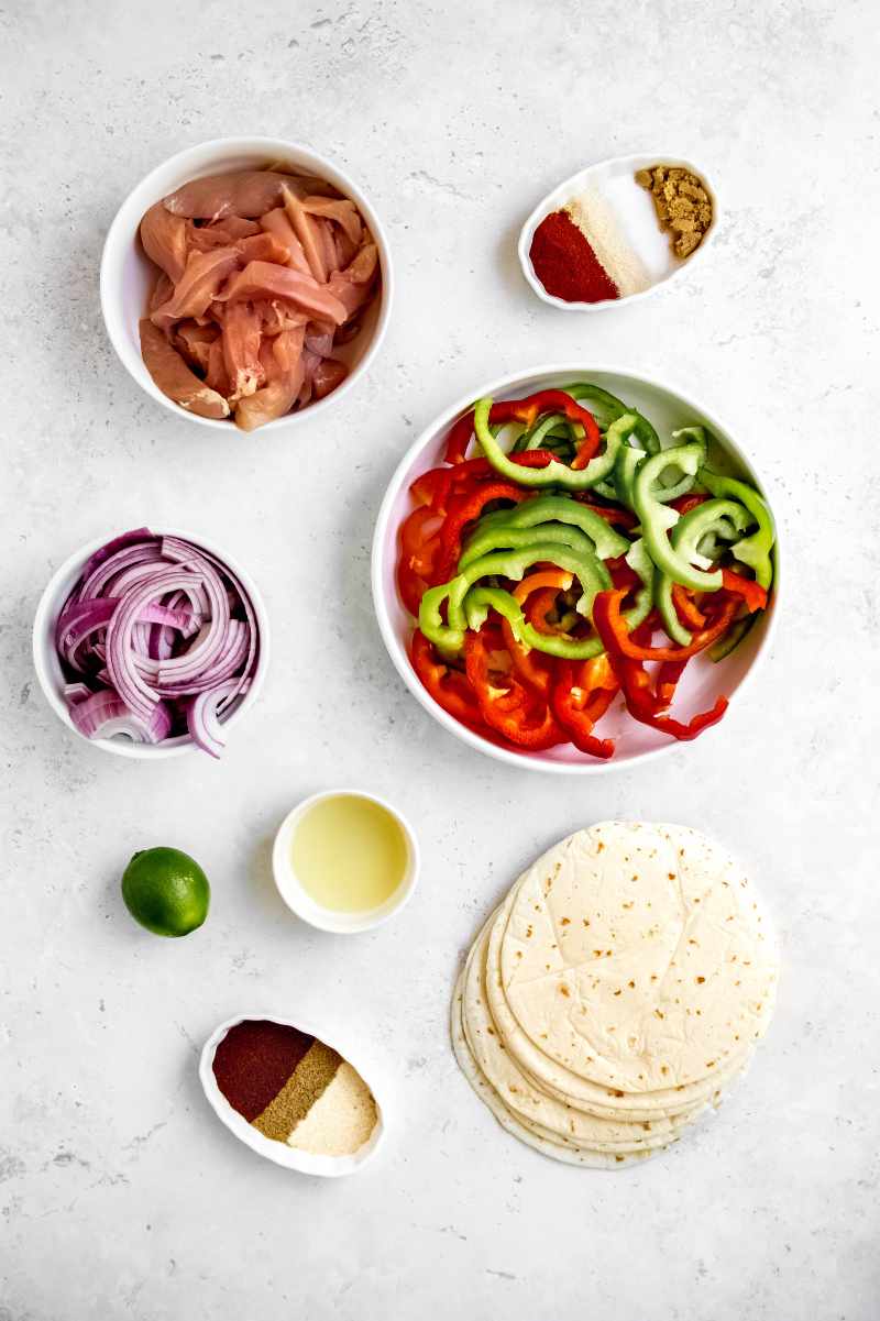 Ingredients including chicken, red onion, and bell peppers all cut into strips.