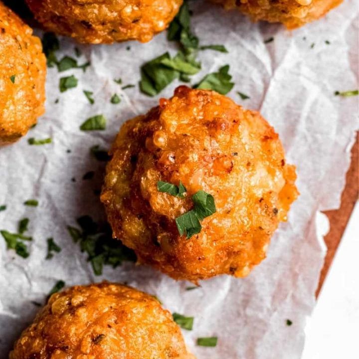 Close view of baked chicken meatballs on a serving board, garnished with chopped fresh herbs.