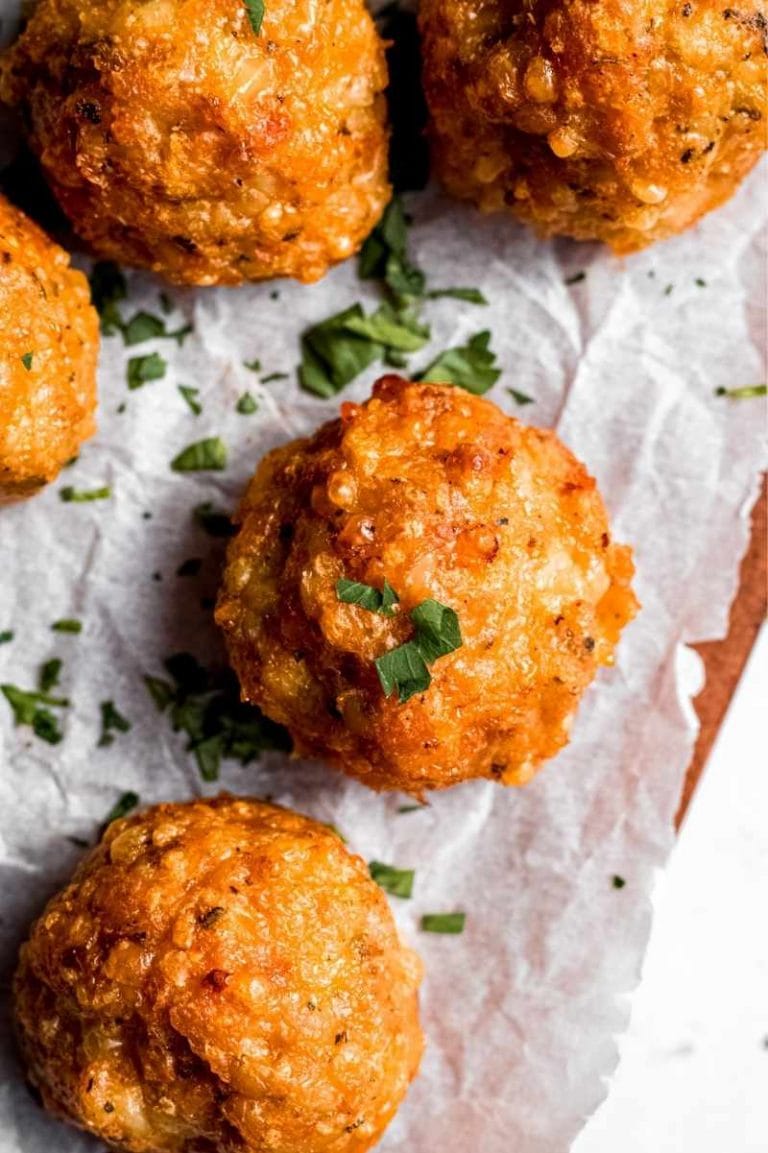 Close view of baked chicken meatballs on a serving board, garnished with chopped fresh herbs.