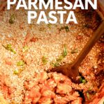 Overhead view of a wooden spoon scooping chicken parmesan pasta from a white enameled dutch oven. A text overlay reads, "Chicken Parmesan Pasta."