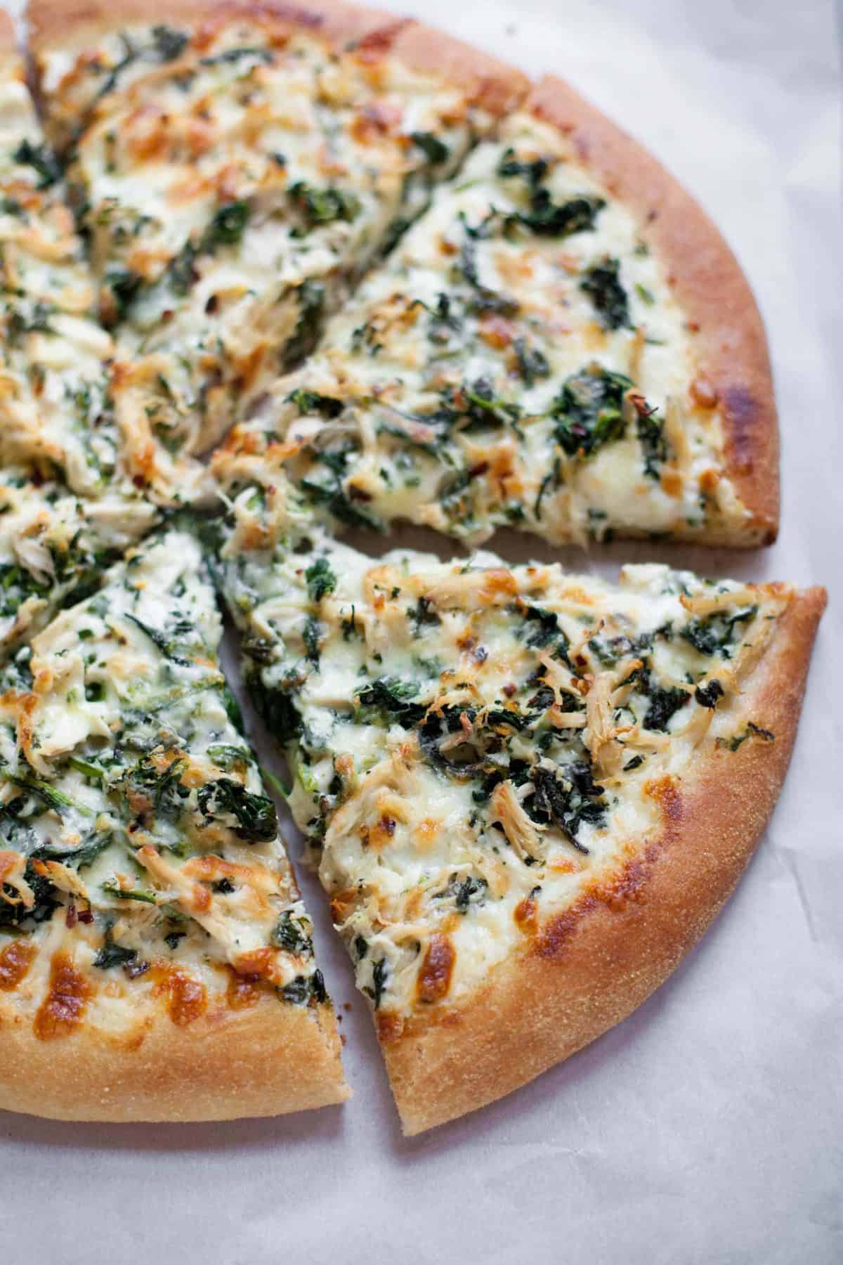 Overhead shot of Chicken Spinach Alfredo Pizza, cut into slices