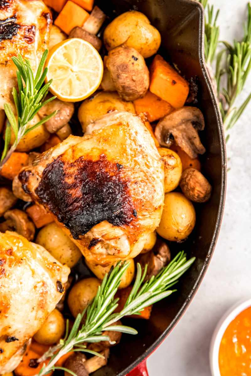 Overhead of a one-pan chicken and veggie skillet with mushrooms halves, sweet potato pieces, and baby potatoes.