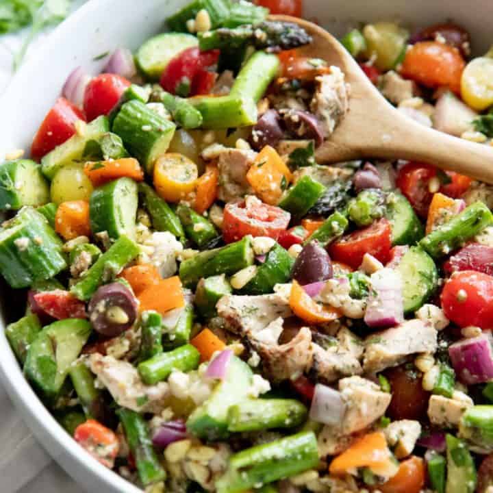 Side angle shot of Grilled Chicken and Asparagus Chopped Greek Salad in a white bowl