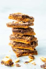 Six pieces of homemade saltine toffee stacked high on a counter.