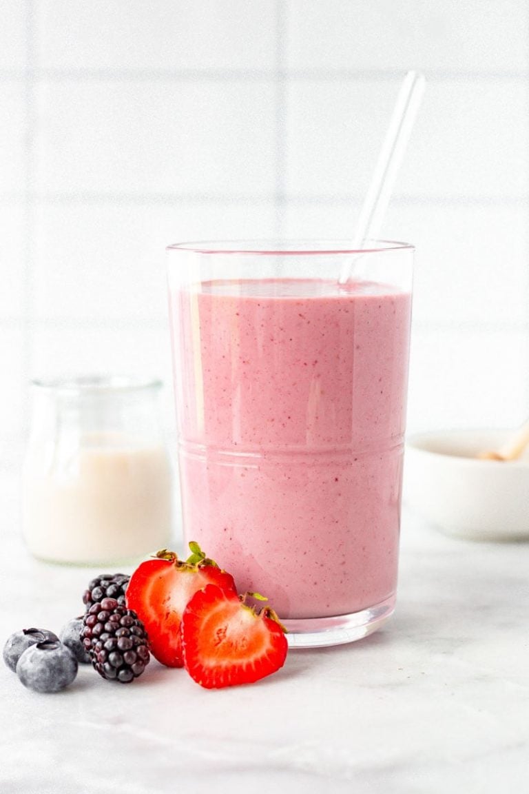 Close up of mixed berry smoothie with fresh berries beside it.