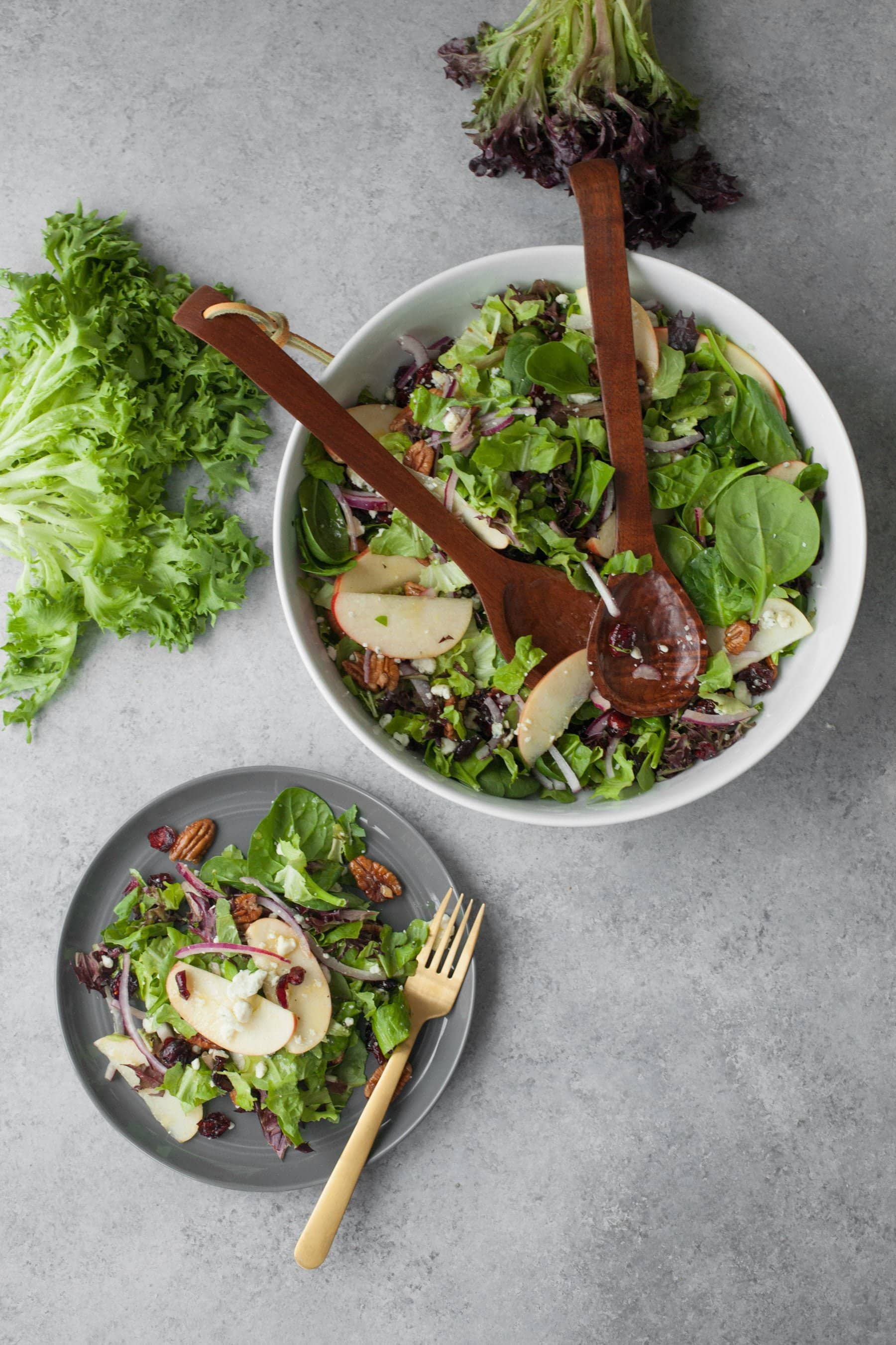 Birdseye view of dishing up cranberry apple pecan salad for thanksgiving from a large serving bowl.