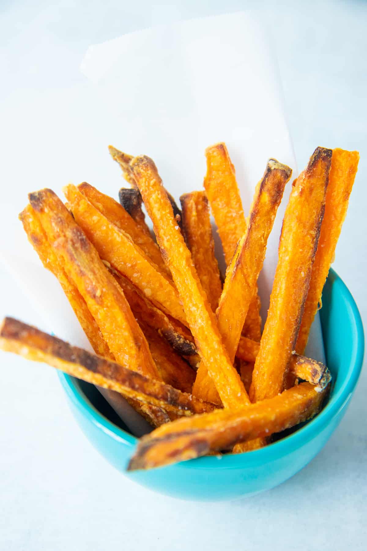 Close up of crispy baked sweet potato fries in a small blue bowl.