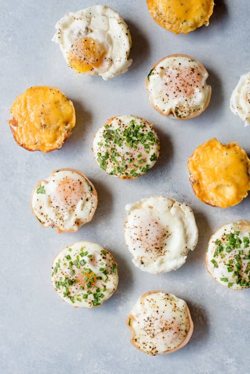 A variety of breakfast egg muffins sit on a gray background.