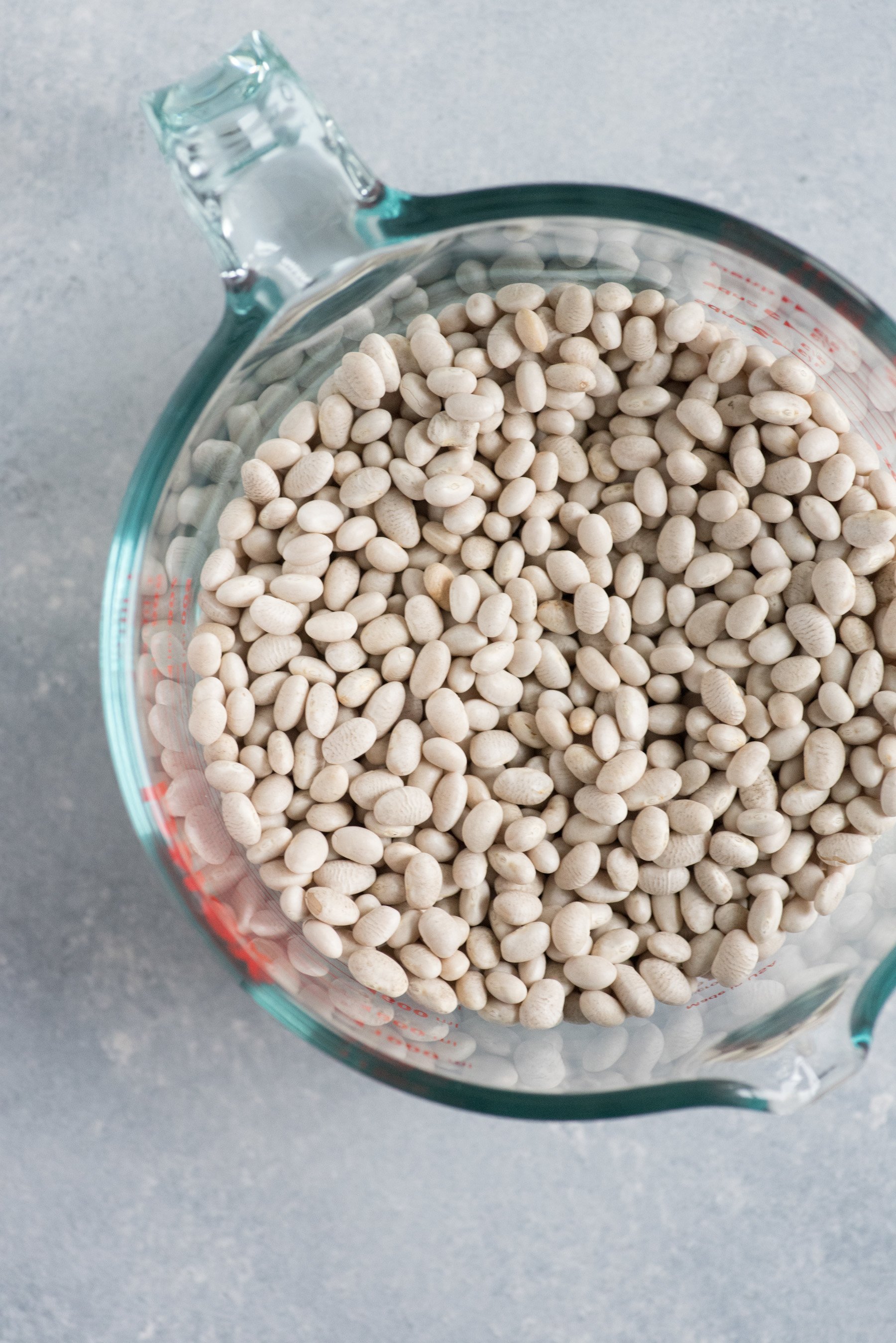 Dried beans sit in a glass measuring cup.