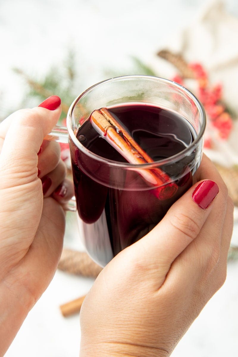 Two hands hug a mug of Christmas wassail.