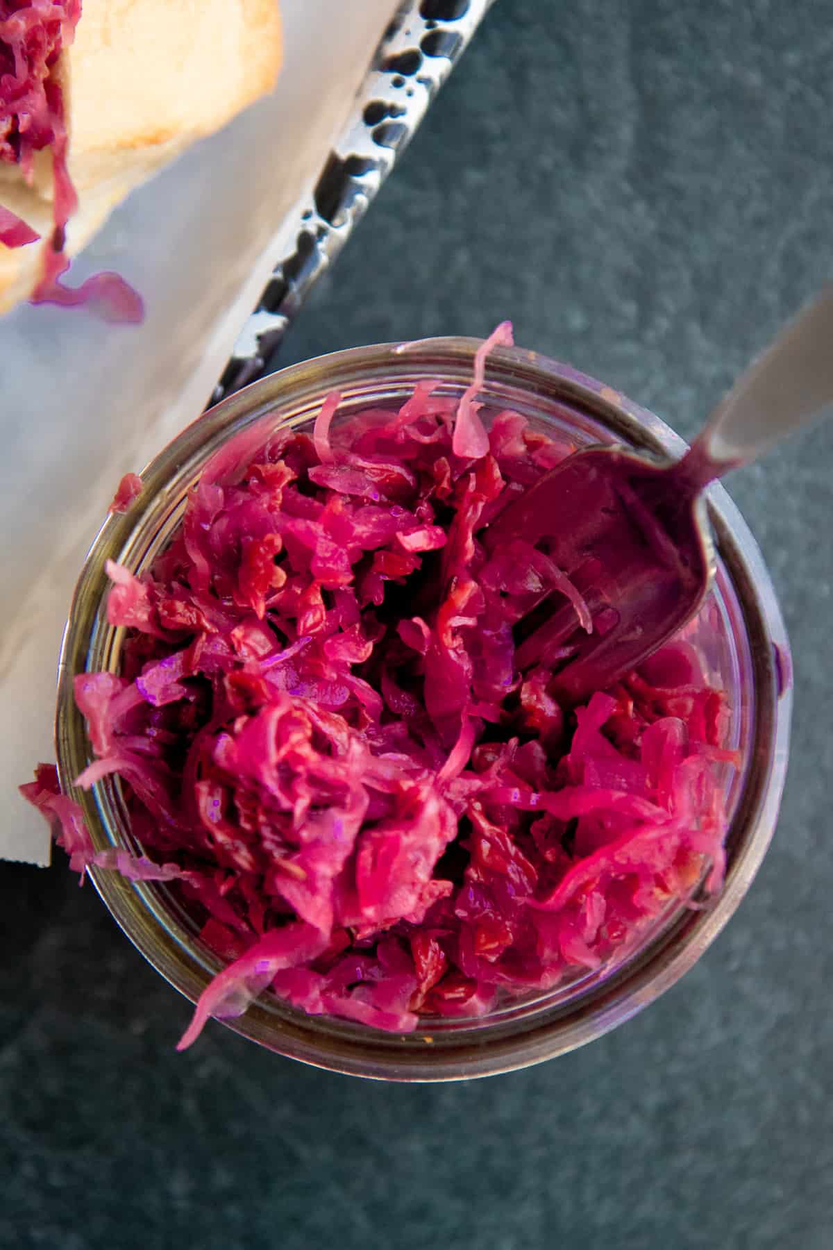 A fork dips into a glass jar of homemade sauerkraut.