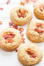 Five bourbon and brown sugar cookies topped with bacon pieces on a white background.