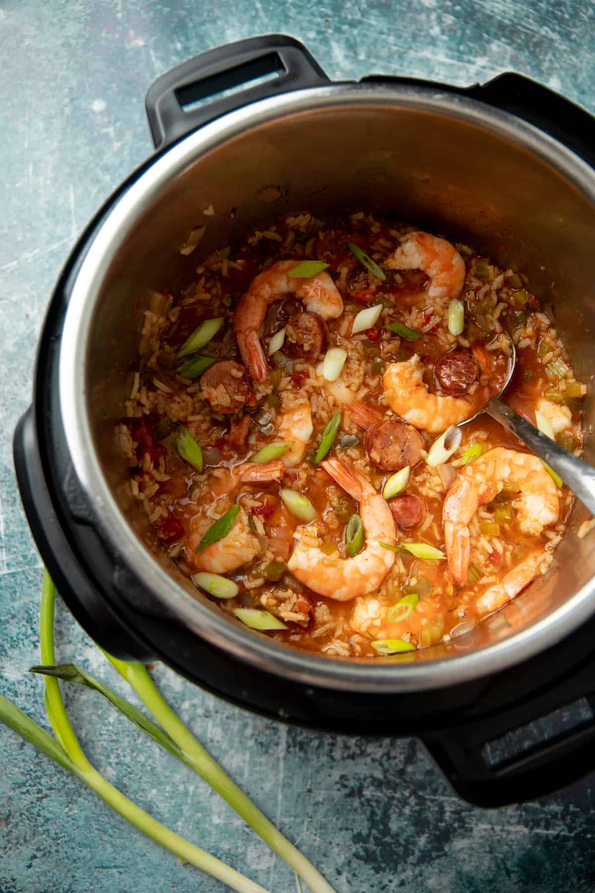 An Instant Pot holds paleo shrimp jambalaya. A silver spoon sits inside the pot.