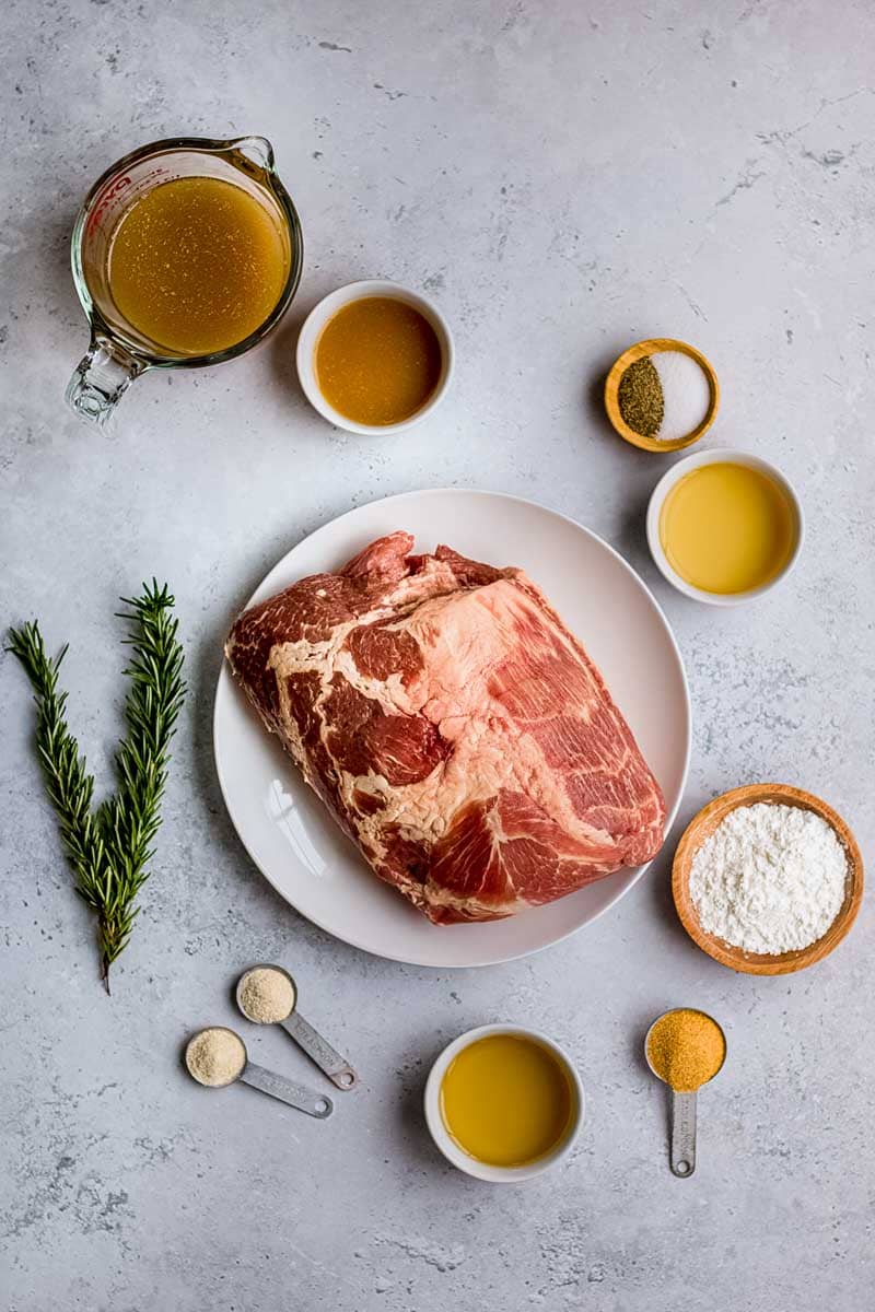 Overhead of ingredients needed to make this recipe, including pork, herbs, and spices.