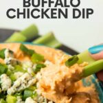 Close view of a stick of celery scooping buffalo chicken dip from a bowl. A text overlay reads, "Instant Pot Buffalo Chicken Dip."