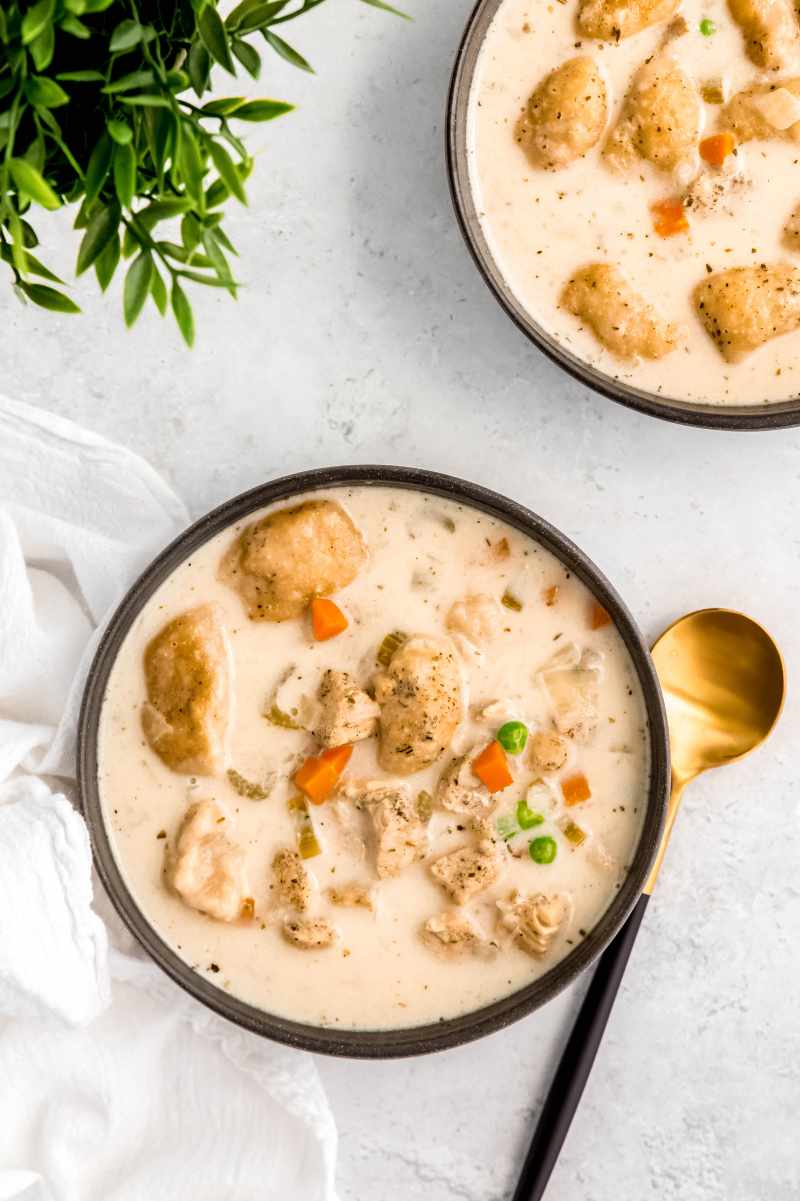 Overhead of a bowl of chicken soup with a spoon resting beside it.