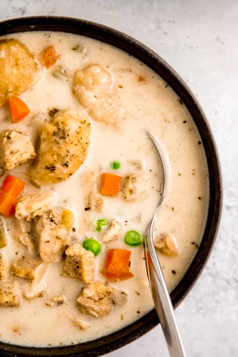 Close view of a spoon resting in a bowl of creamy chicken soup.