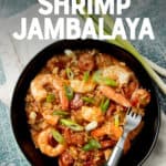 A piece of sausage rests on a fork inside a bowl of jambalaya. Whole green onions lay alongside the bowl. A text overlay reads "Instant Pot Shrimp Jambalaya. With Paleo and Whole30 Options."