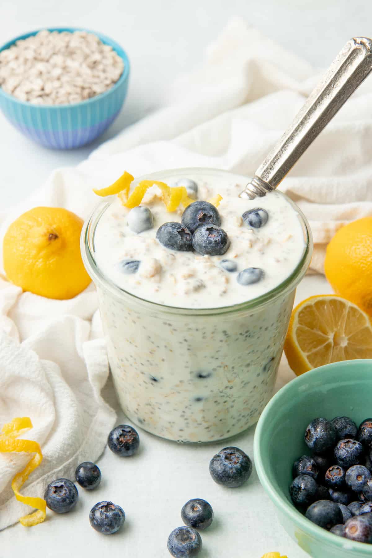 A spoon rests in a glass jar of blueberry overnight oatmeal.