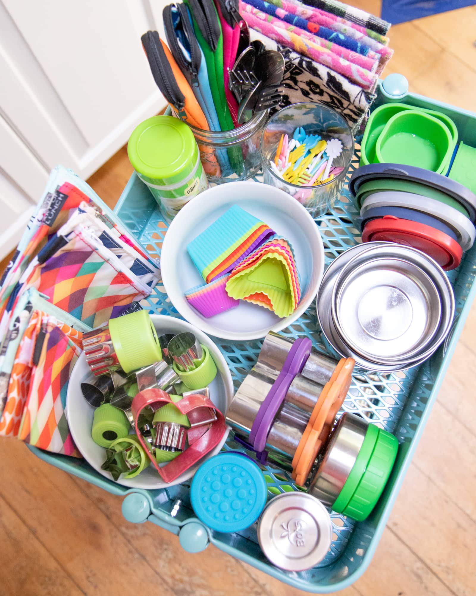 Shelf of a utility cart holding small containers and accessories for zero-waste lunch packing.