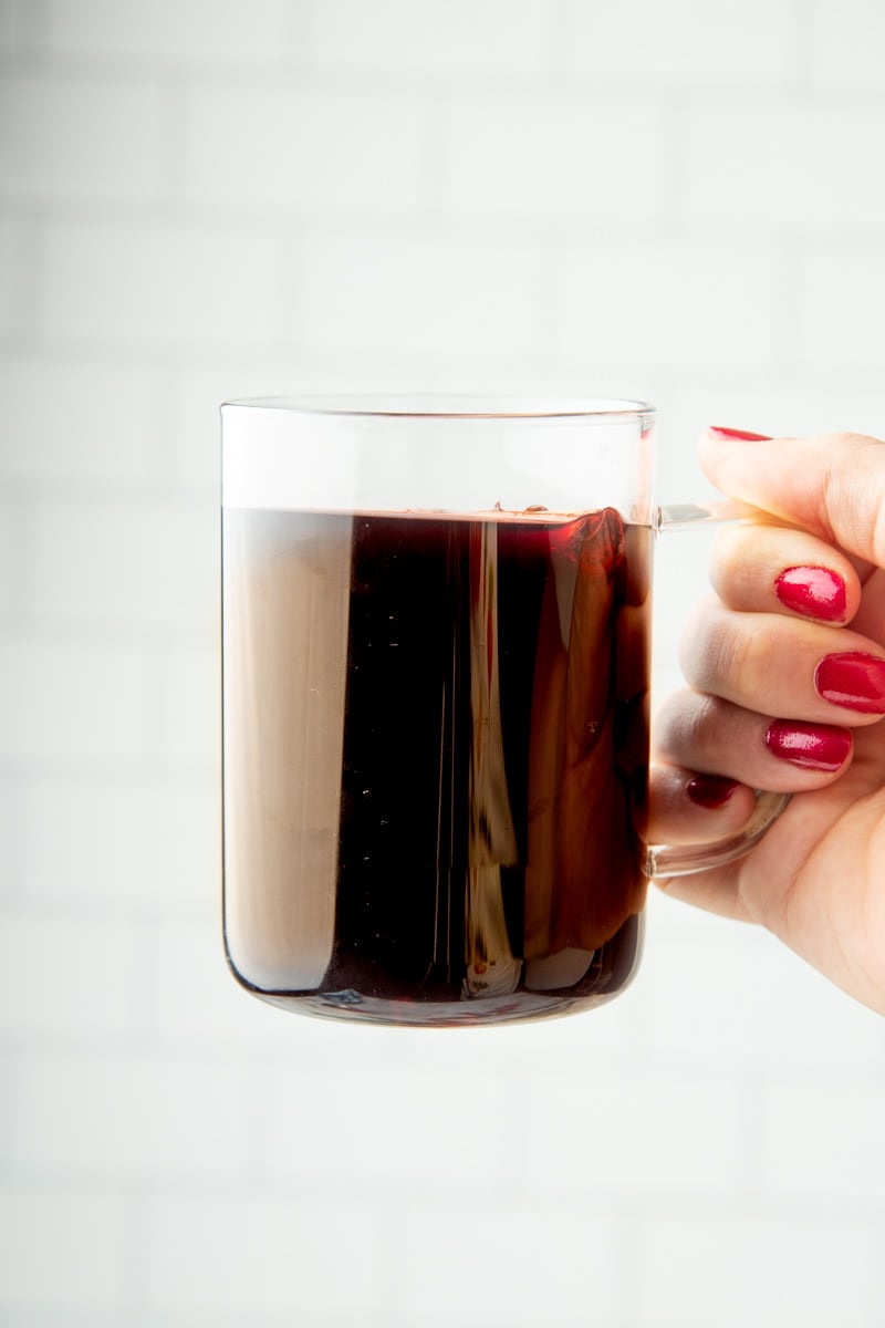 Hand holding up a mug of mulled wine by the handle.