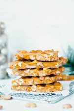 Close view of pieces of homemade peanut brittle stacked tall on a parchment paper lined cooling rack.