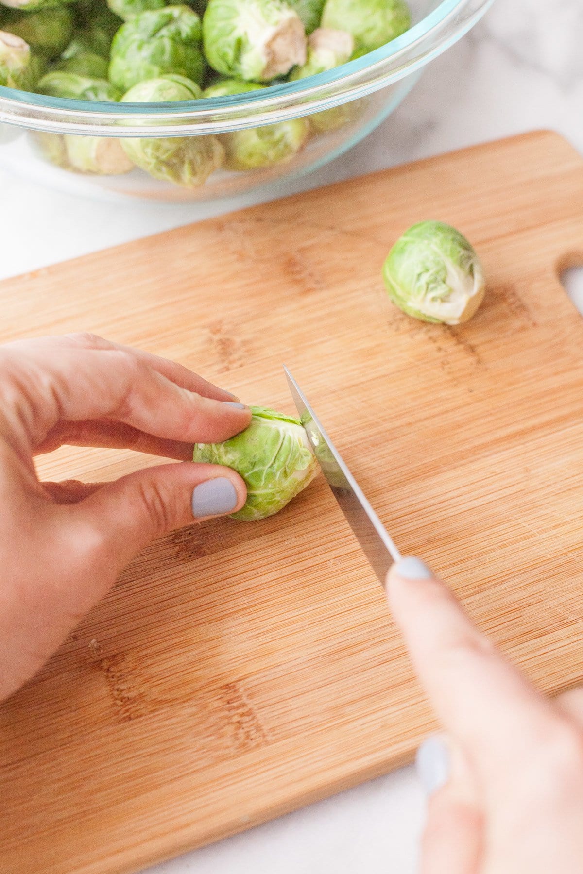 Hands cut the stem end off a brussel sprout