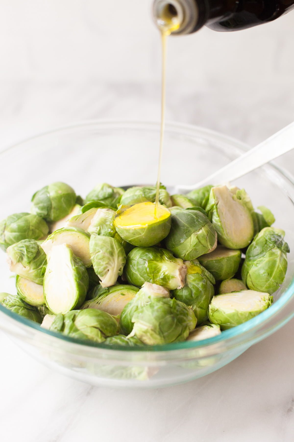 Oil drizzles over a bowl of vegetables