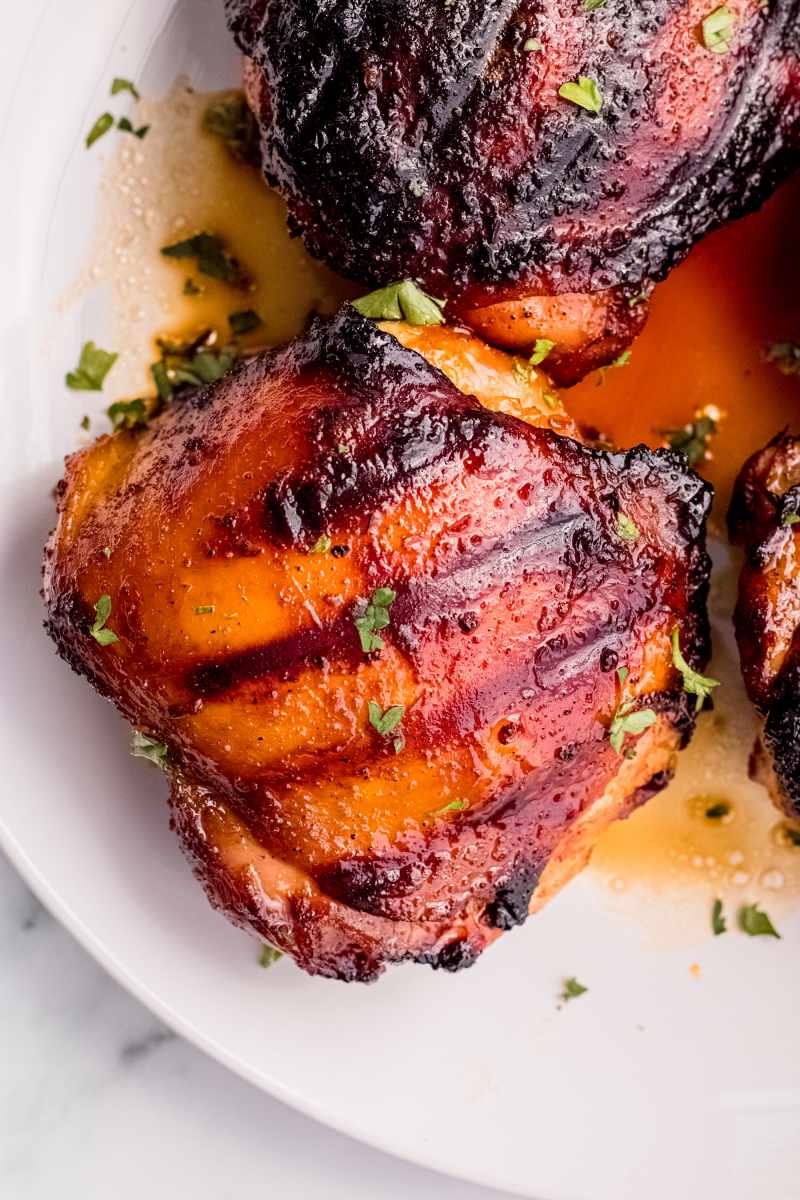 Close view of finished grilled chicken on a plate garnished with chopped fresh parsley.