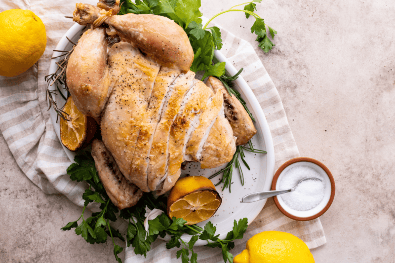 A roasted chicken with crispy skin, with slices made through the breasts