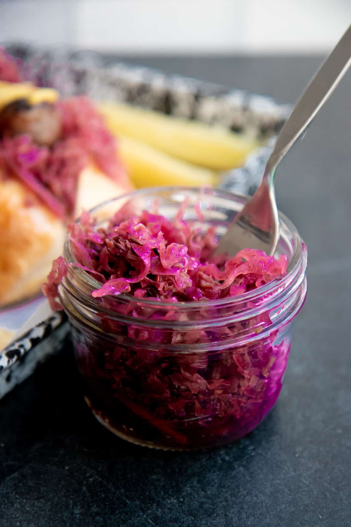 Red sauerkraut in a wide mouth mason jar with a fork resting in the jar.