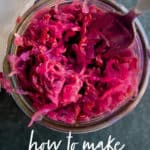 A fork dips into a glass jar of homemade sauerkraut. A glass overlay reads "How to Make Sauerkraut."