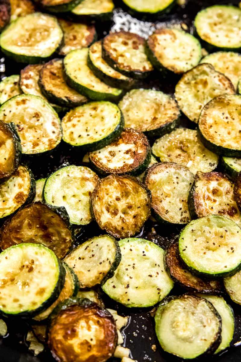 Close view of sauteed zucchini with garlic in a cast iron skillet.