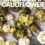 A metal spatula scoops up roasted broccoli and cauliflower from a parchment paper lined sheet pan. A text overlay reads, "Sesame Roasted Broccoli & Cauliflower."