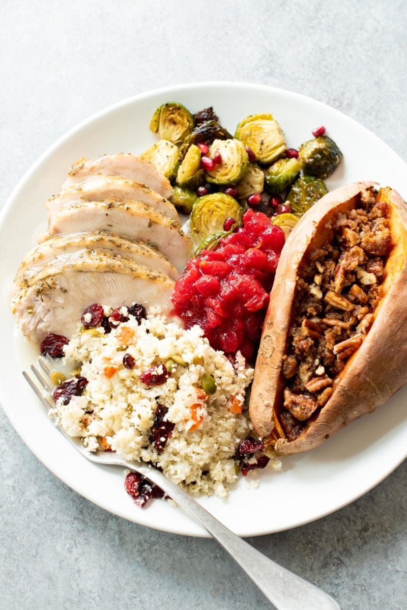 Plate of Thanksgiving food - turkey, Brussels sprouts, cranberry sauce, sweet potatoes, and cauliflower rice pilaf