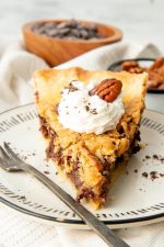 Front view of a single slice of bourbon pecan pie on a white plate.