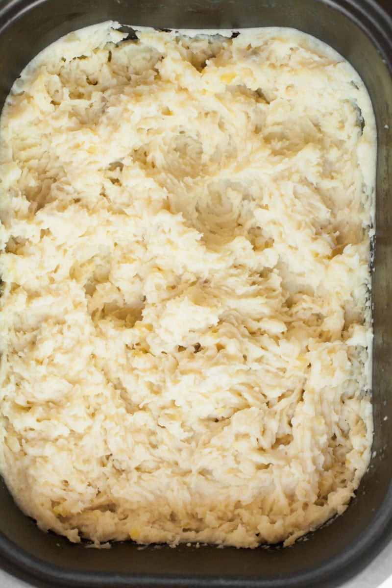 Closeup view of fluffy mashed potatoes in a large Crock-Pot. Mashed potatoes are topped with fresh chives.