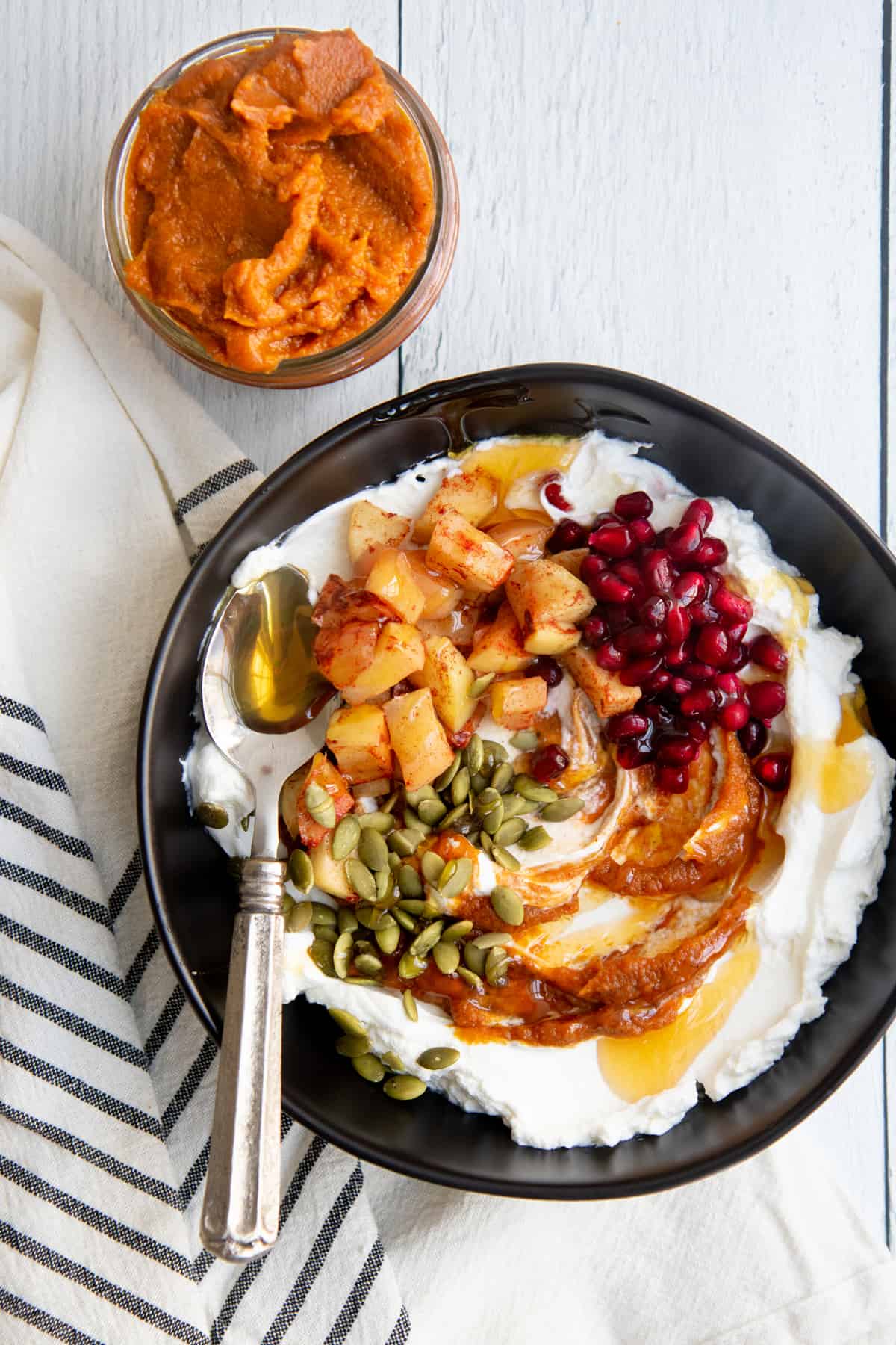 Yogurt topped with pumpkin butter and fruit in a black bowl.