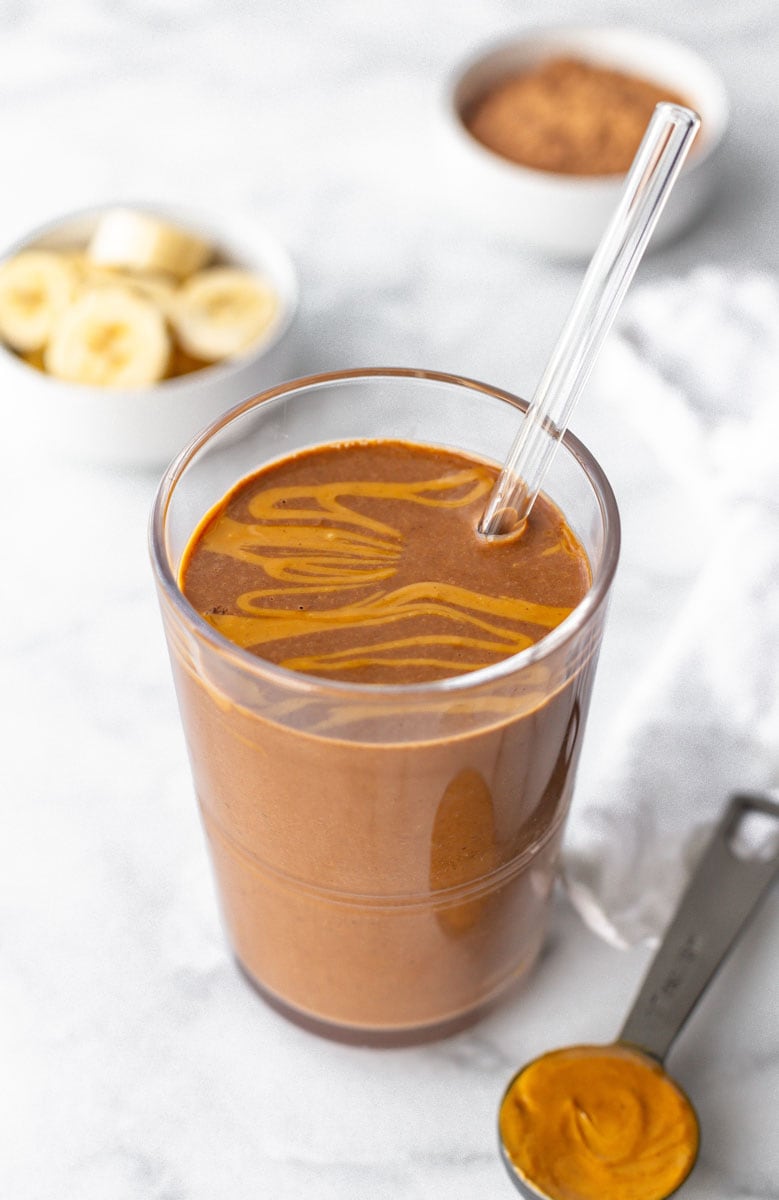 Close-up of finished smoothie in a glass with a reusable glass straw.