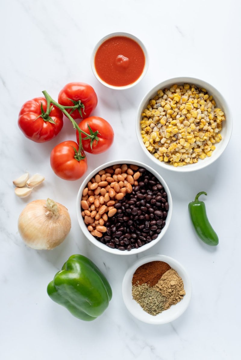 Overhead shot of ingredients for Slow Cooker Summer Chicken Chili - tomatoes, beans, rice, onions, peppers