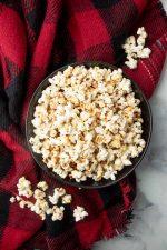 Top view of a black bowl piled high with sweet and salty popcorn.