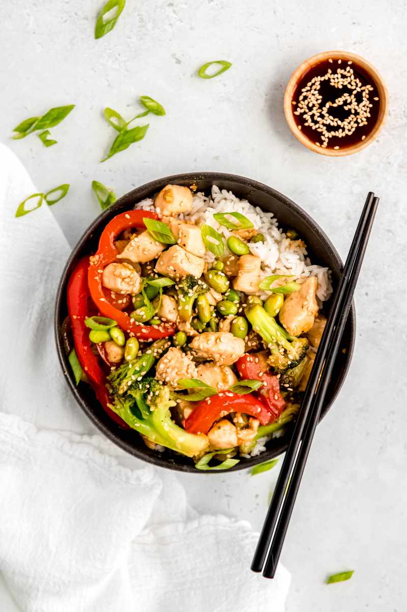 Top view of a teriyaki chicken dinner served over rice and garnished with sesame seeds and green onions sliced on the bias.