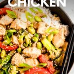 Close view of chopsticks resting along the side of a dark bowl filled with white rice topped with teriyaki chicken and vegetables. A text overlay reads, "Teriyaki Chicken."