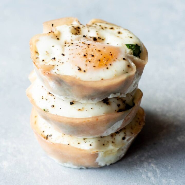 Three spinach egg cups stacked atop one another on a light background.