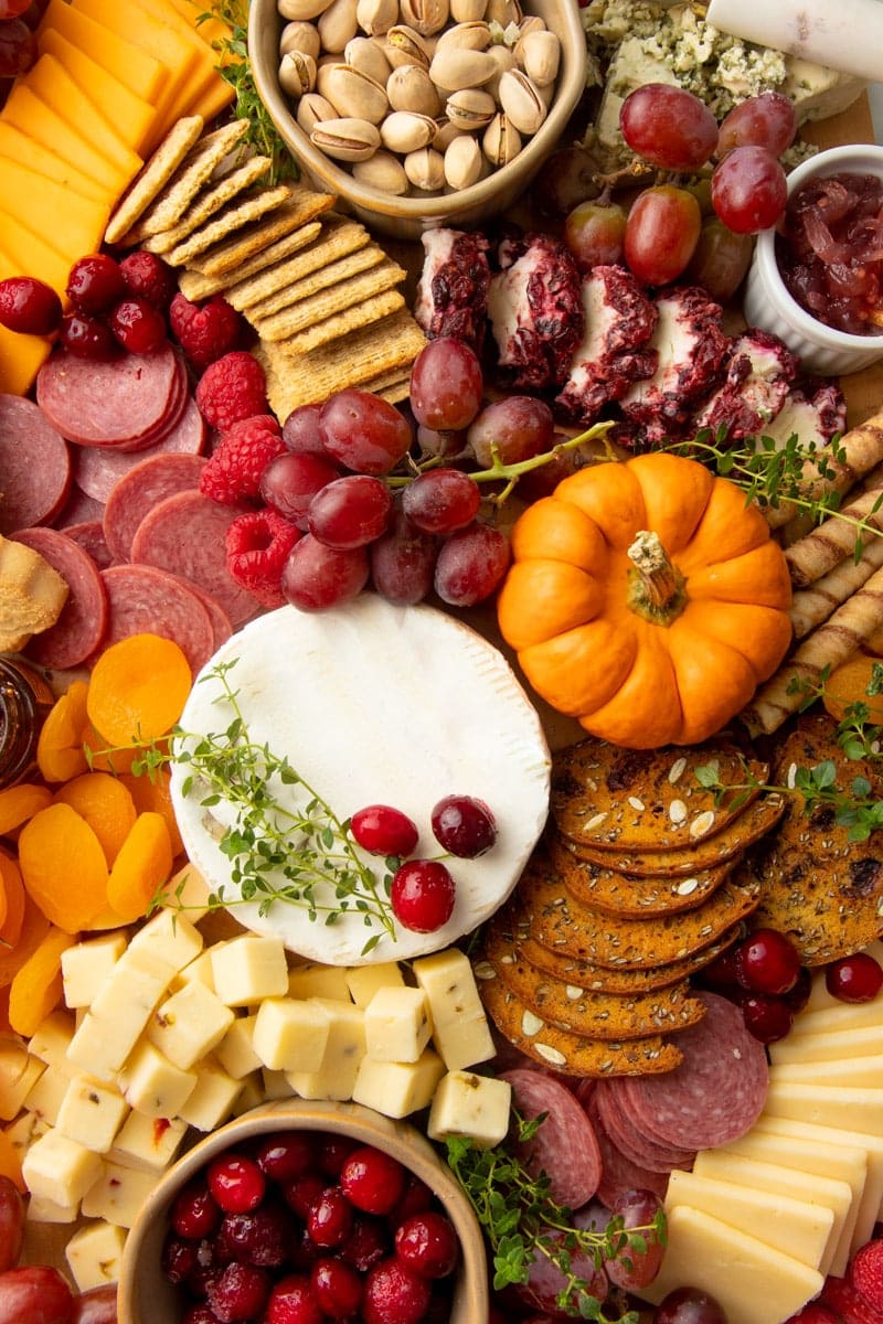 Close view of a seasonal snack board perfect for Thanksgiving, with cheese, meat, crackers, and fruits.